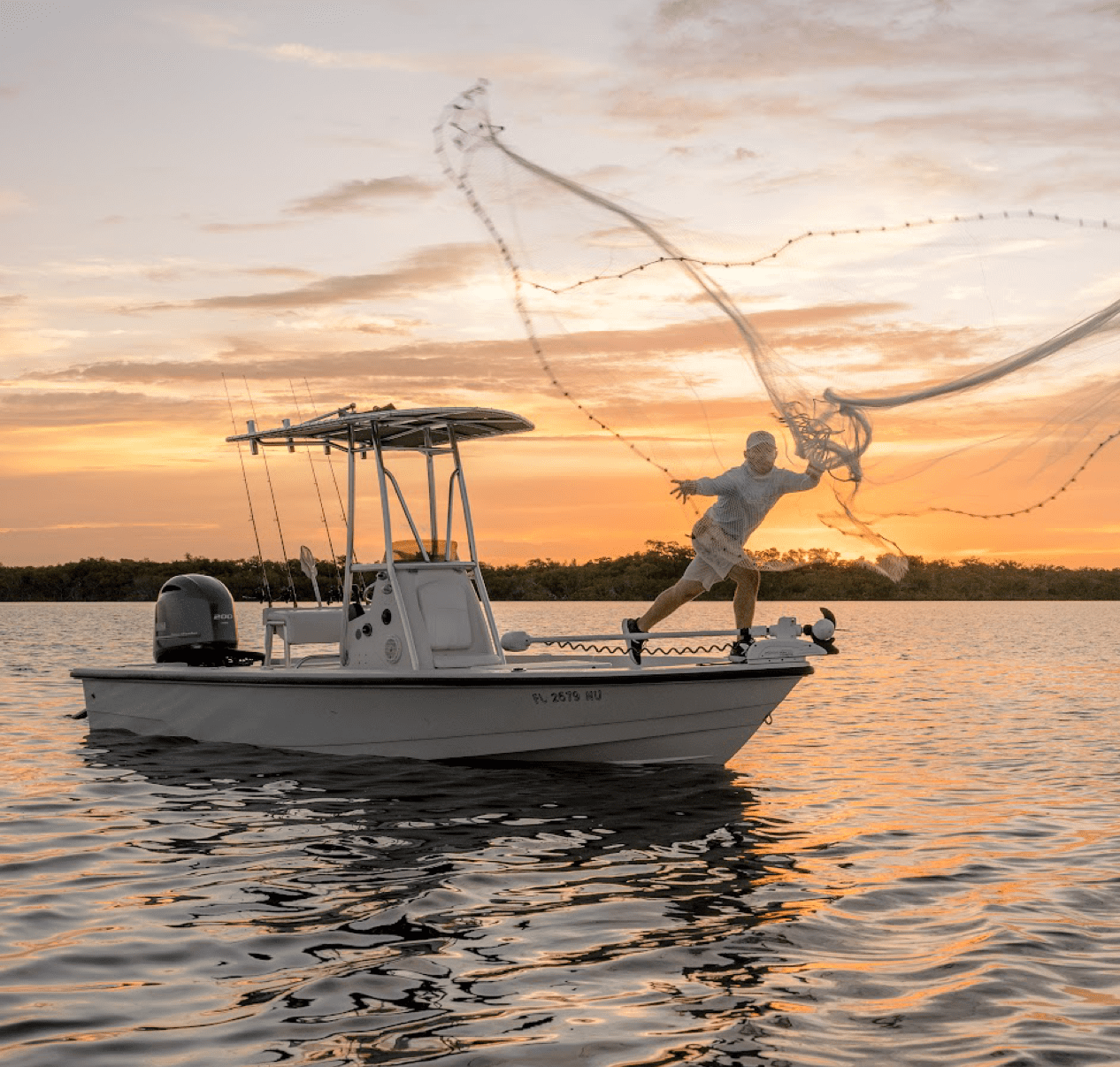 Captain Drew casting a net off the side of a boat