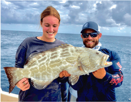 Man and woman holding Goliath Grouper