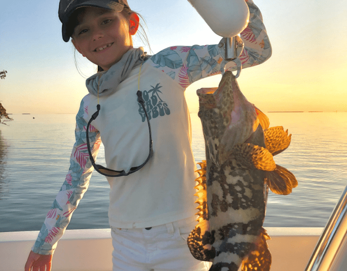 Young girl holding fish at sunset