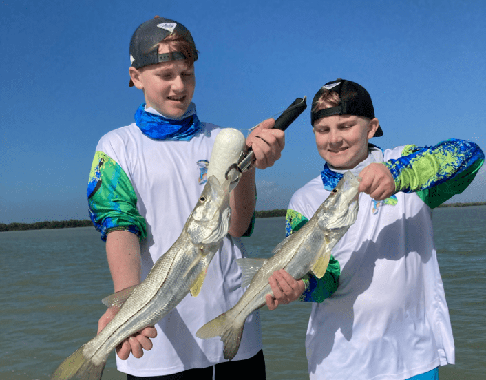 Two young boys hold fresh fish captured