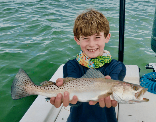 Male child posing with a fish on a boat