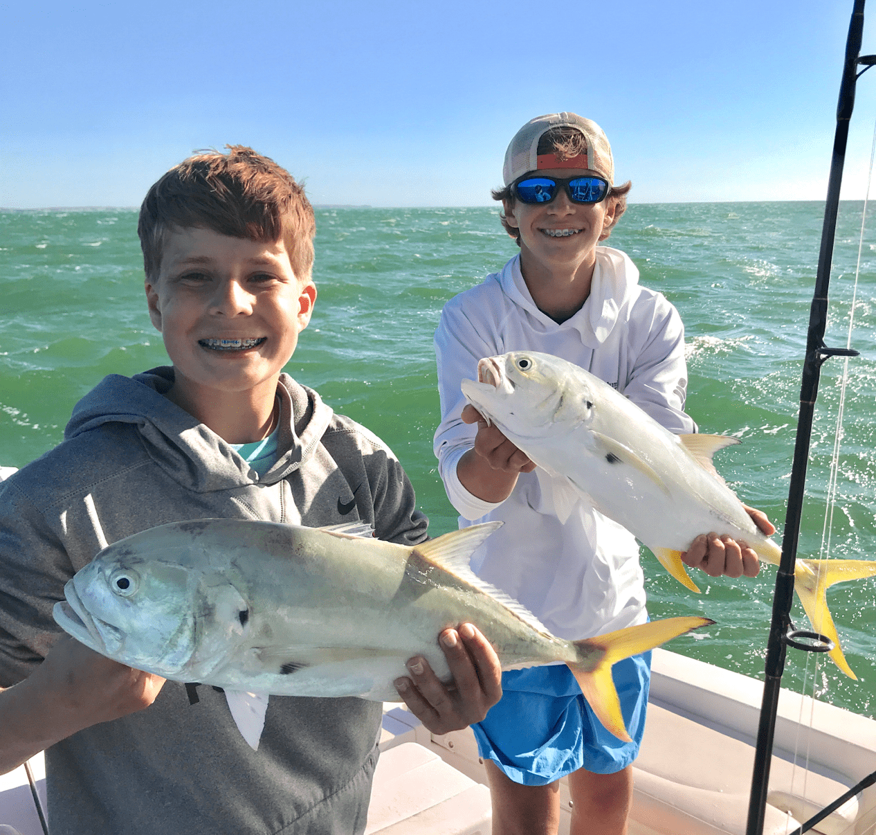 Two male teenagers posing on the water with fish