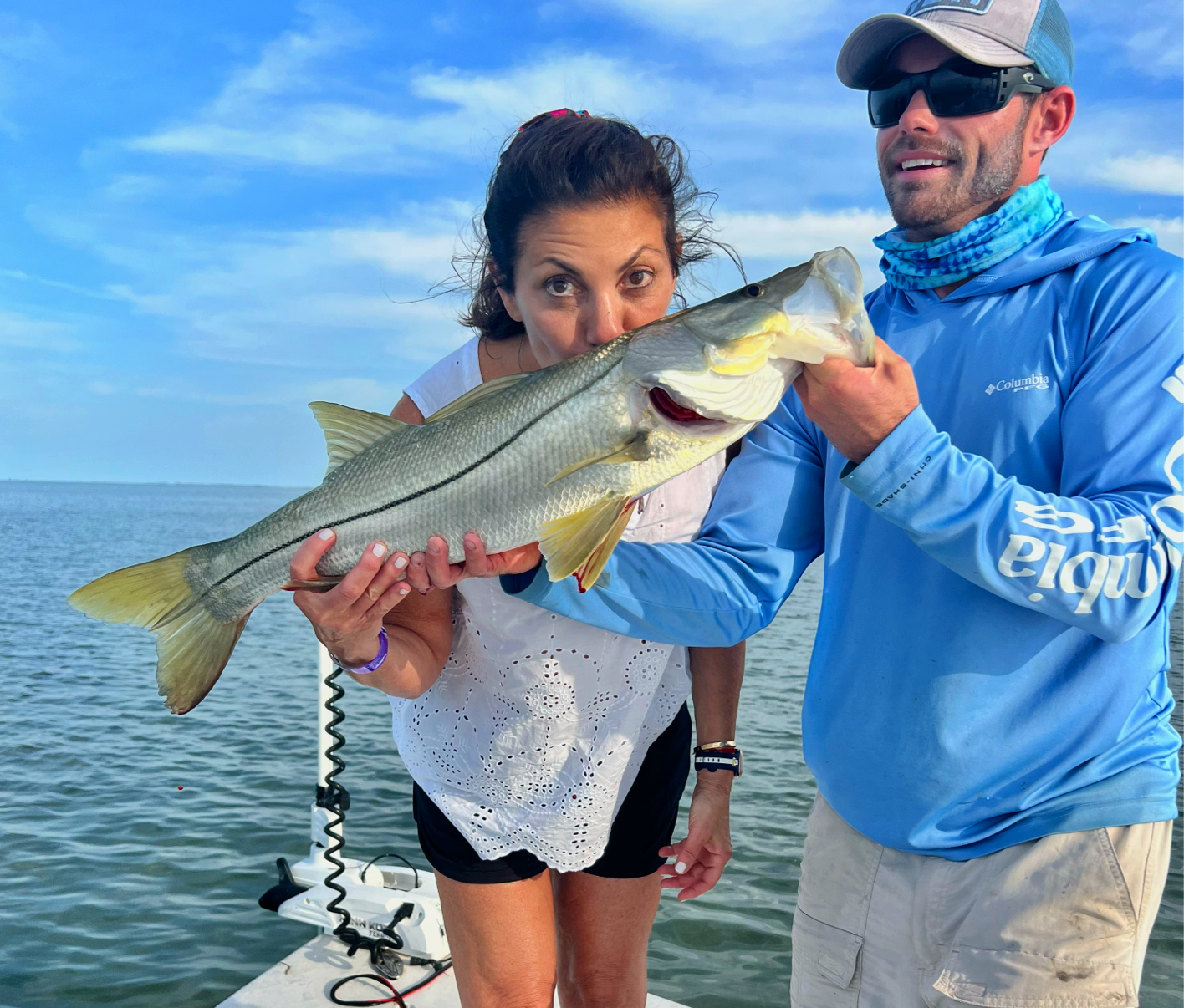 Captain Drew helping hold a fish with woman